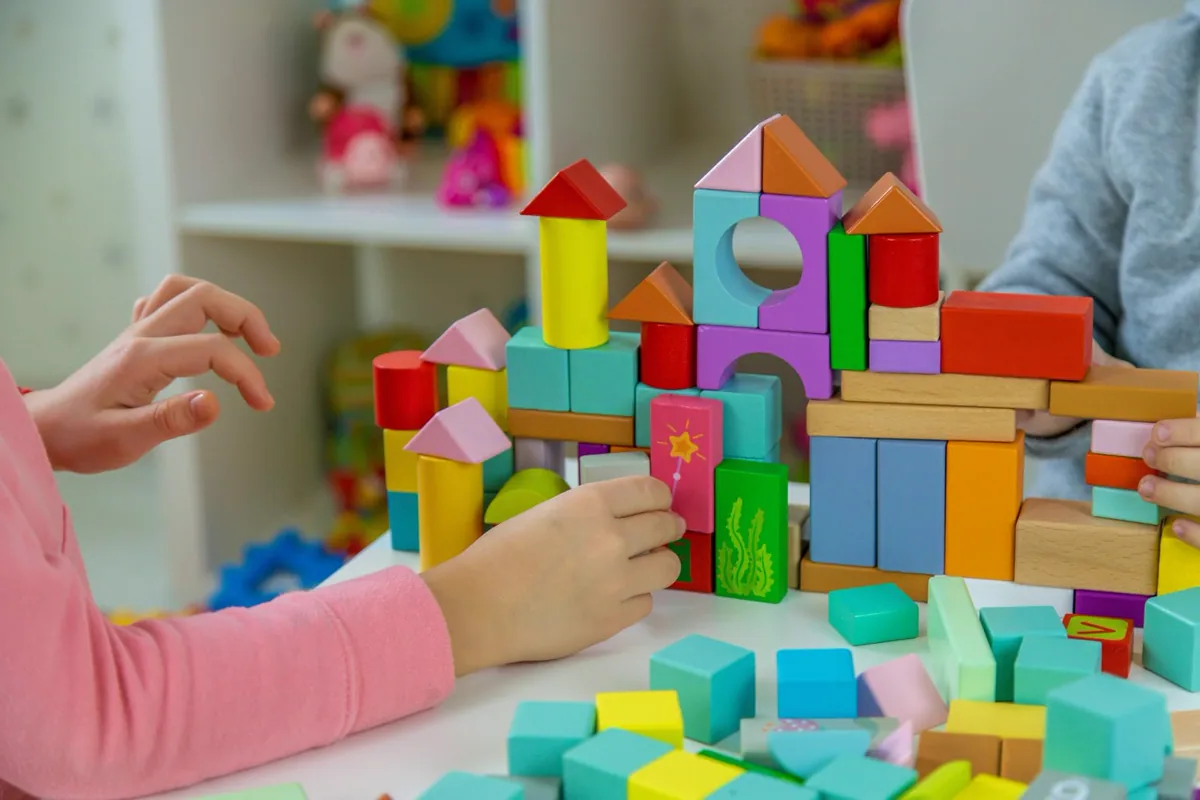 Children building colourful towers with wooden toy blocks at Mokids Shop